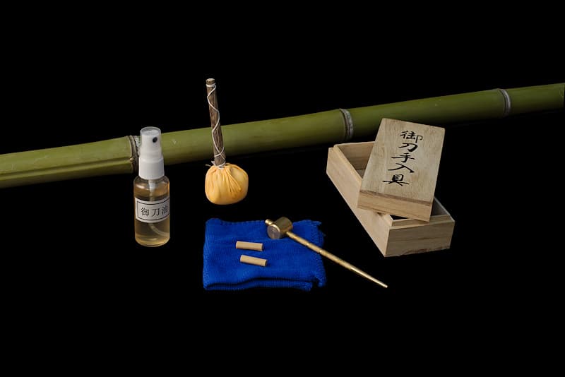 Protective oil, micro-fiber, chalk ball (Uchiko), pin remover (Mekugi Nuki) and pins (Mekugi), delivered in a wooden box | I have the privilege of maintaining the katanas of the best samurai. I maintain the blade to protect it from oxidation. Unalloyed steel (without additives such as chromium and molybdenum) is prone to rust. An alloy of iron and carbon, steel is weakened by the presence of oxygen. Air can therefore attack it, which is why my oil helps protect the surface of this noble metal.