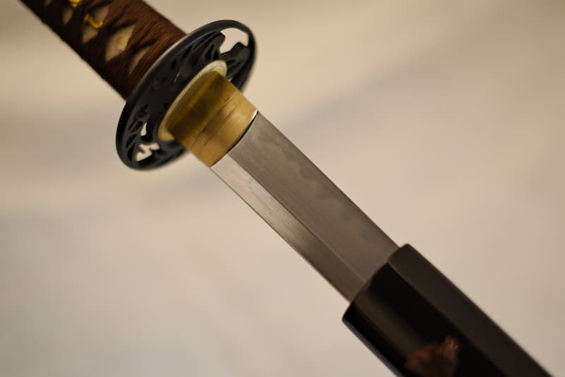 Sharp katana, extra-hard steel (1095), genuine temper line (hamon 刃文), with black scabbard (saya 鞘), delivered in a composite wood case containing a maintenance kit, lacquered stand and protective cloth cover | Carried by my samurai master, I have crisscrossed the earth to the point that my new mount bears the trace of it. The brown rope is now the symbol of my name, Seishi (聖地 Sacred Earth).