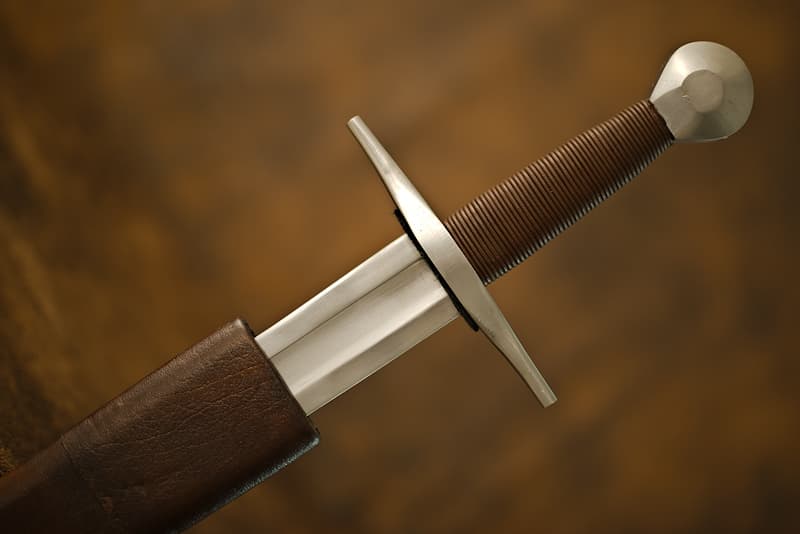 Forged medieval sword, short throat blade, leather-covered handle, cylindrical pommel, wood and leather scabbard