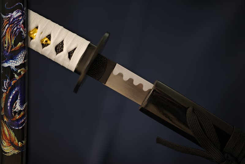 Collection Katana Tsuka-Ito (柄糸) white and Sageo (下緒) black, Saya (鞘 scabbard) black with dragon silkscreen | Legend has it that I am mysterious, visible only to the chosen few I choose. White in the light, black at night, I disappear like the dragon adorning my scabbard (鞘 Saya), between sea waves and the highest clouds.