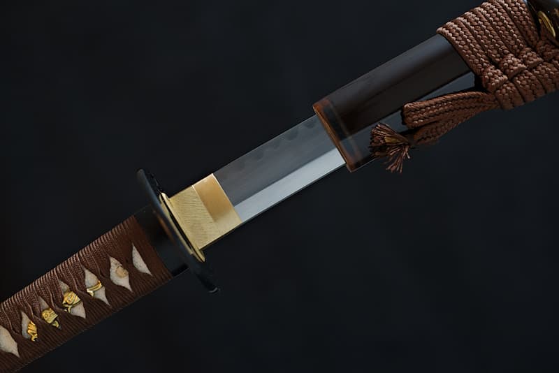 Sharp Katana, extra-hard steel (1095), hand-sharpened, genuine temper line (Hamon 刃文), with brown scabbard (Saya 鞘), koiguchi (鯉口), Kurigata (栗形) and Kojiri (鐺) in natural horn, delivered in a wooden case containing a maintenance kit, lacquered stand and protective cloth cover
