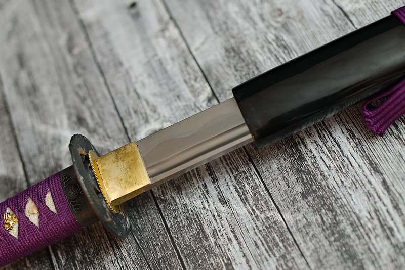 Sharp katana with varnished wooden scabbard, purple ito (柄糸) and sageo (下緒), delivered with protective cloth cover | Tapered and razor-sharp, I'm meant for the elite. My purple frame would have made any samurai dream.