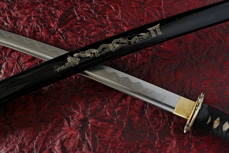 Sharpened Katana with scabbard (Saya 鞘) engraved (Japanese composition with dragon), black Tsuka-Ito (柄糸) and Sageo (下緒), blade engraved (the 7 virtues of the Bushidō), supplied with protective cloth cover, in composite wooden case with varnished wooden stand with protections and maintenance kit | I embody the values of the samurai. The engravings I wear represent the seven fundamental values that Inazō Nitobé ascribed to the Way of the Warrior, the Bushidō (武士道): righteousness, courage, benevolence, politeness, sincerity, honor and loyalty.