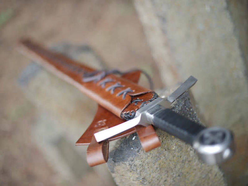 Medieval crossed knight's sword set on natural vertical stones Medieval crossed knight's sword set on natural vertical stones