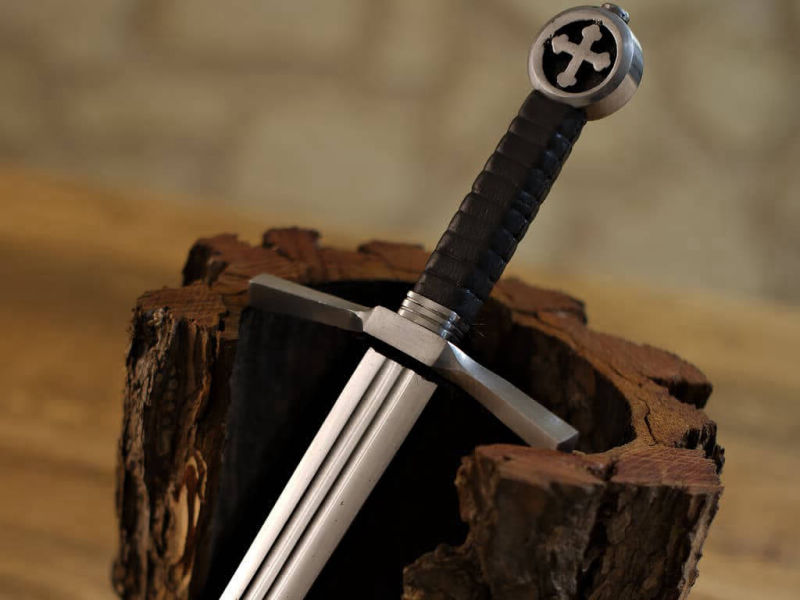 Medieval Crusader knight's dagger set on natural bark in a medieval setting