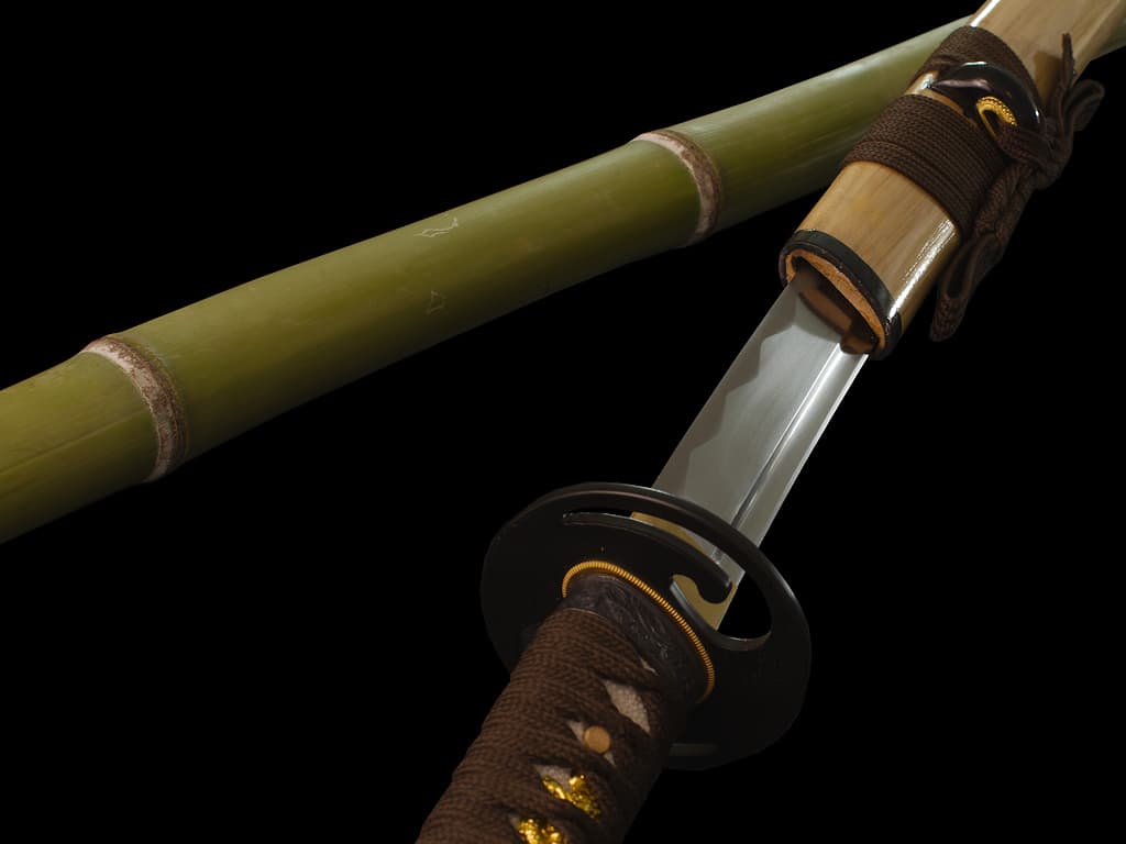 Mù-jīn, sharpened wakizashi wood (mù, 木) metal (jīn, 金): detail of the blade emerging from its scabbard (saya), resting on natural bamboo