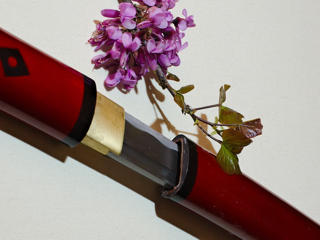 Kaji, fire shirasaya (火事), damascened forge: blade and frame set on a white cloth with a flowery branch Kaji, fire shirasaya (火事), damascened forge: blade and frame set on a white cloth with a flowery branch