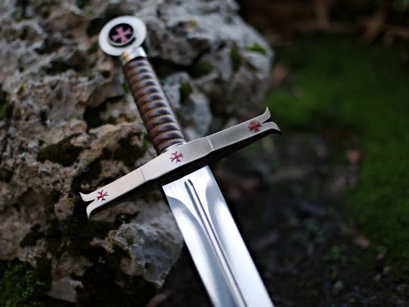 Decorative Templar sword on a rock with a moss background Decorative Templar sword on a rock with a moss background