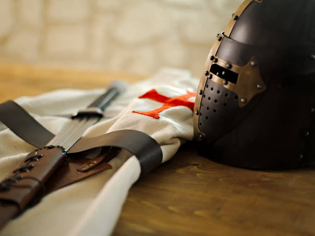 Templar black helmet on a medieval beaker table, with Templar tabard and battle sword