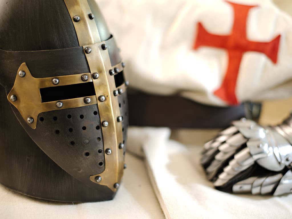 Templar black helmet with riveted brass cross, presented with a Templar tabard and a pair of medieval gauntlets.
