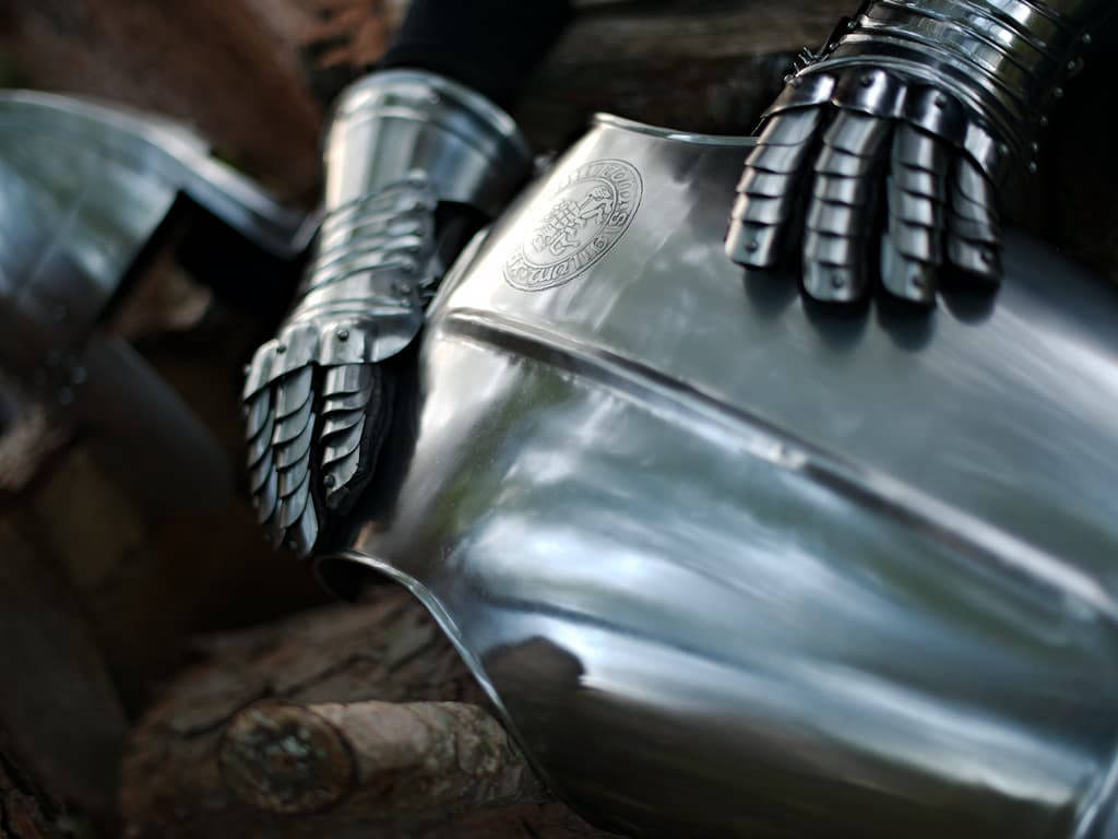 Breastplate with embossed Templar seal, staged with a pair of gauntlets and a medieval helmet Breastplate with embossed Templar seal, staged with a pair of gauntlets and a medieval helmet