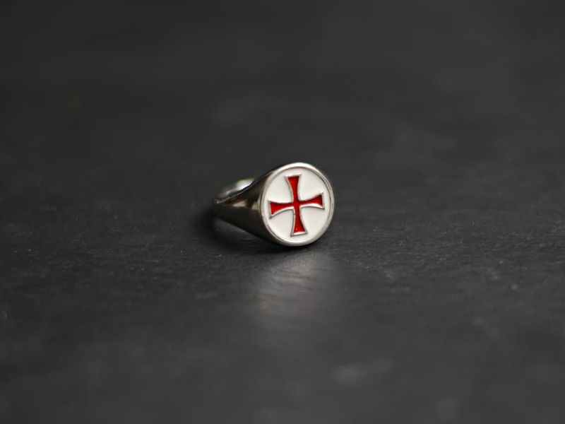 A hand protected by a medieval gauntlet takes possession of the decorative Templar sword. Red Templar cross ring #Terressens