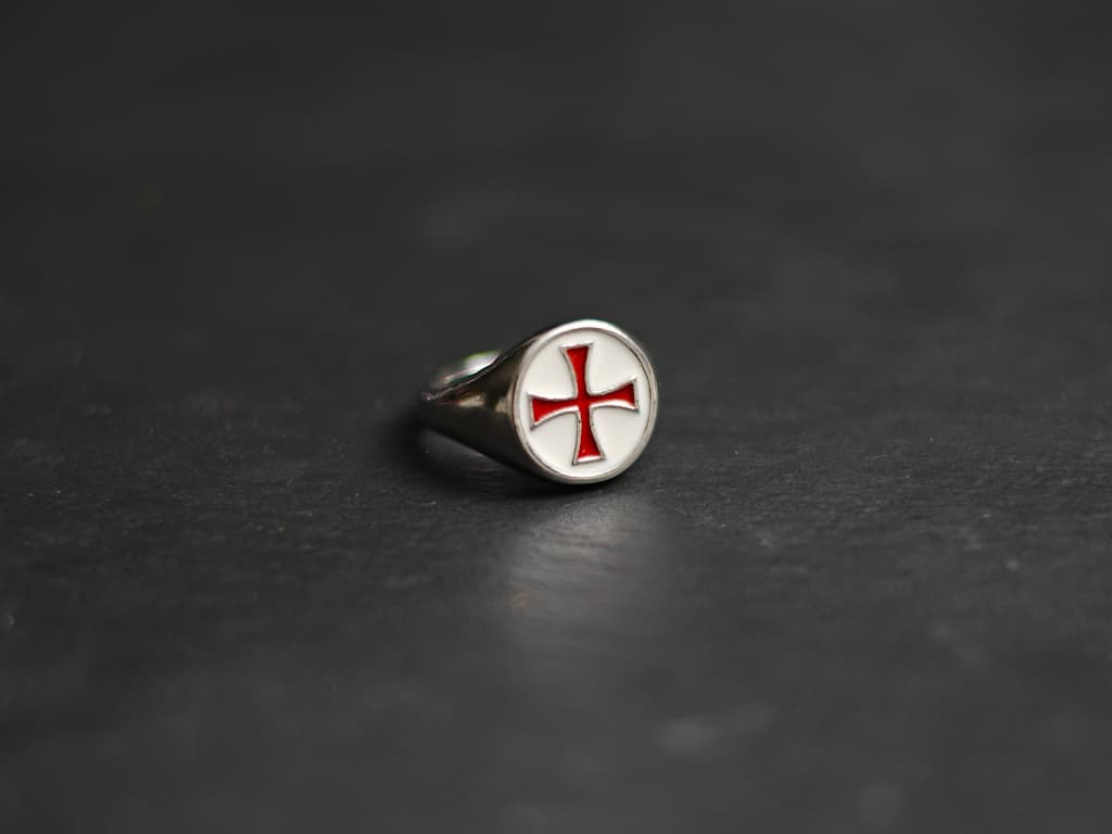A hand protected by a medieval gauntlet takes possession of the decorative Templar sword. Red Templar cross ring #Terressens