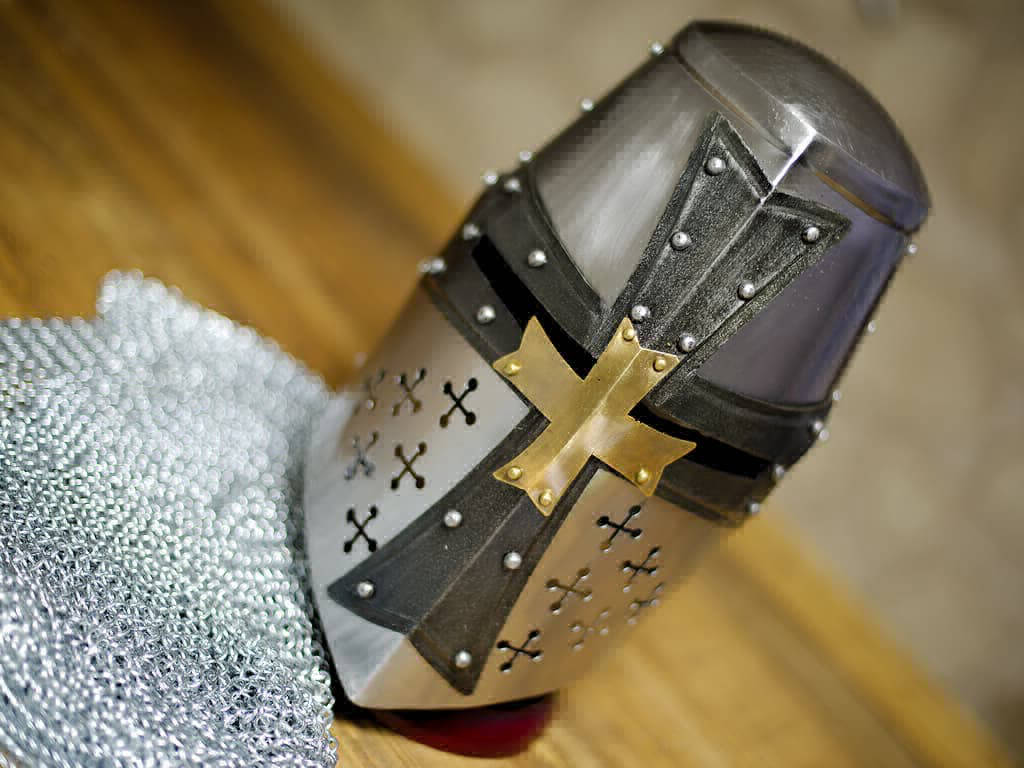 Heaume templier en acier, croix noire et laiton posé sur une table et une cotte de mailles médiévale Heaume templier en acier, croix noire et laiton posé sur une table et une cotte de mailles médiévale